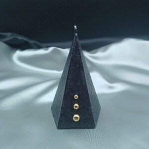 Bougie pyramidale noire Aura Noël avec texture cristallisée et trois perles dorées décoratives sur fond gris satiné.