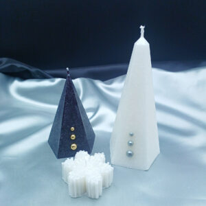 Coffret Noël avec bougie Aura noire, bougie Aura blanche et bougie flocon de neige, photographié sur fond satin argenté.