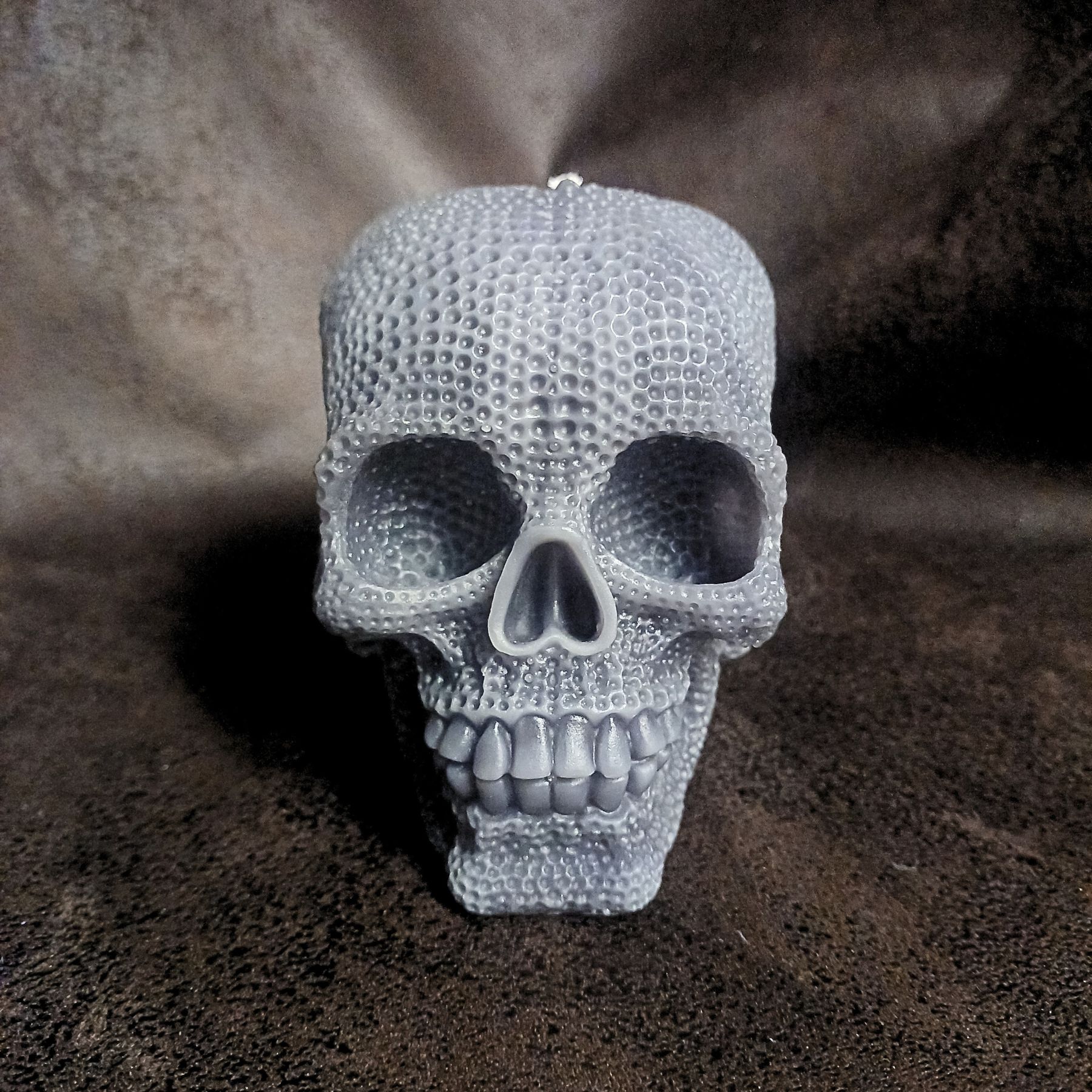 Bougies crâne Le Gardien - Bougie XXL, couleur grise posée sur fond sombre